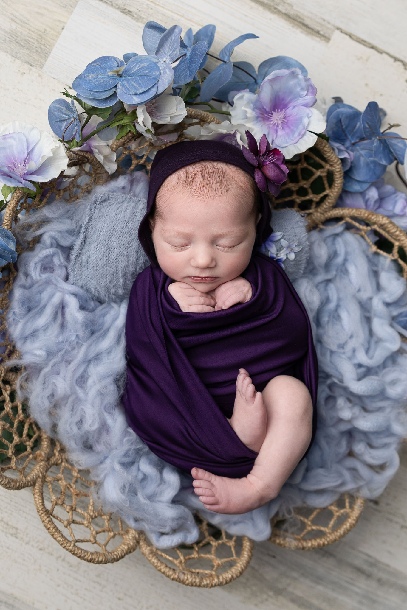 Baby girl in purples sleeps soundly during her studio newborn session.