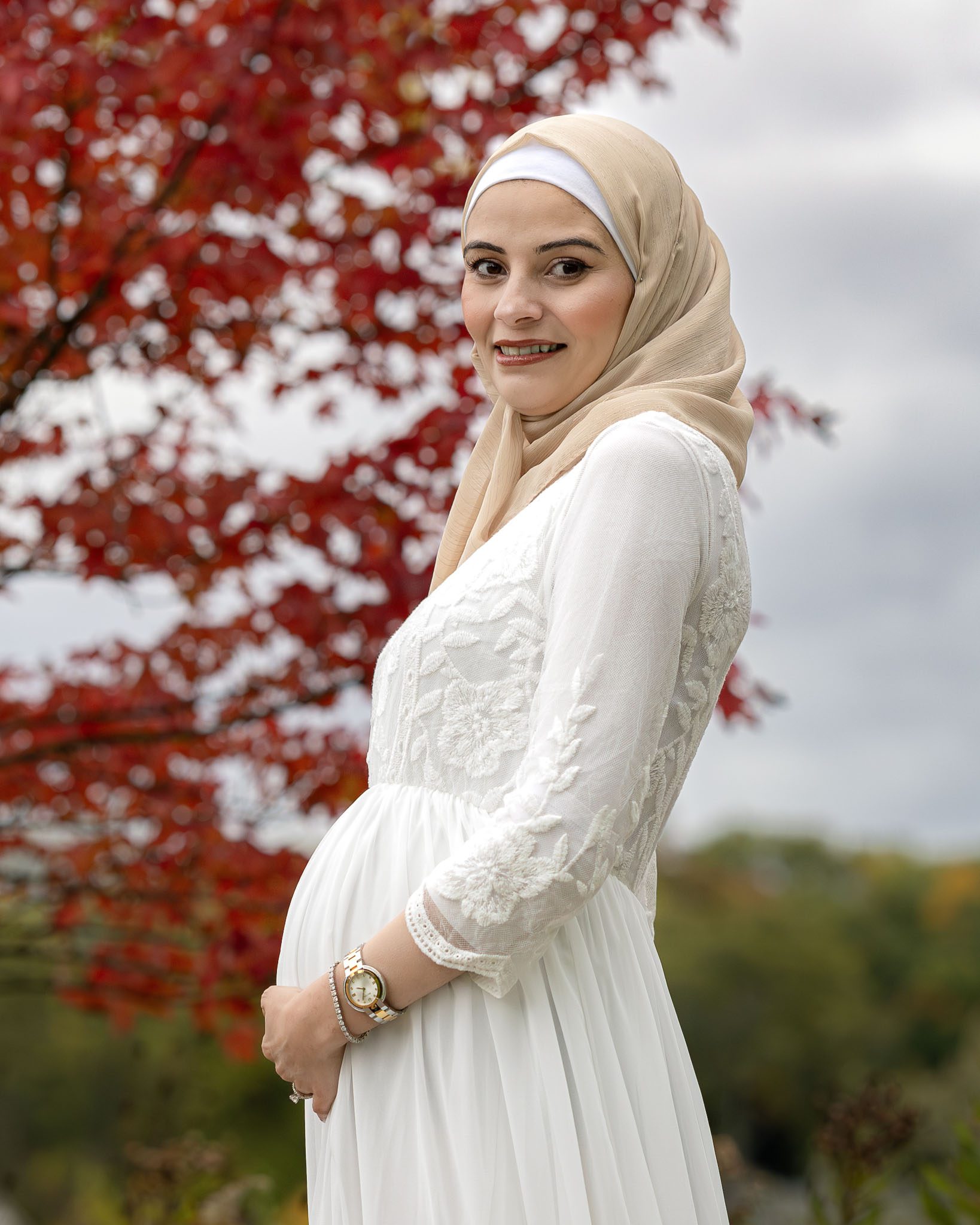 A pregnant mom holds her belly during a fall maternity session at Marshbank Park.